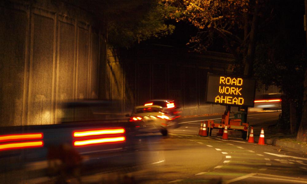 A dark road with a road work sign.